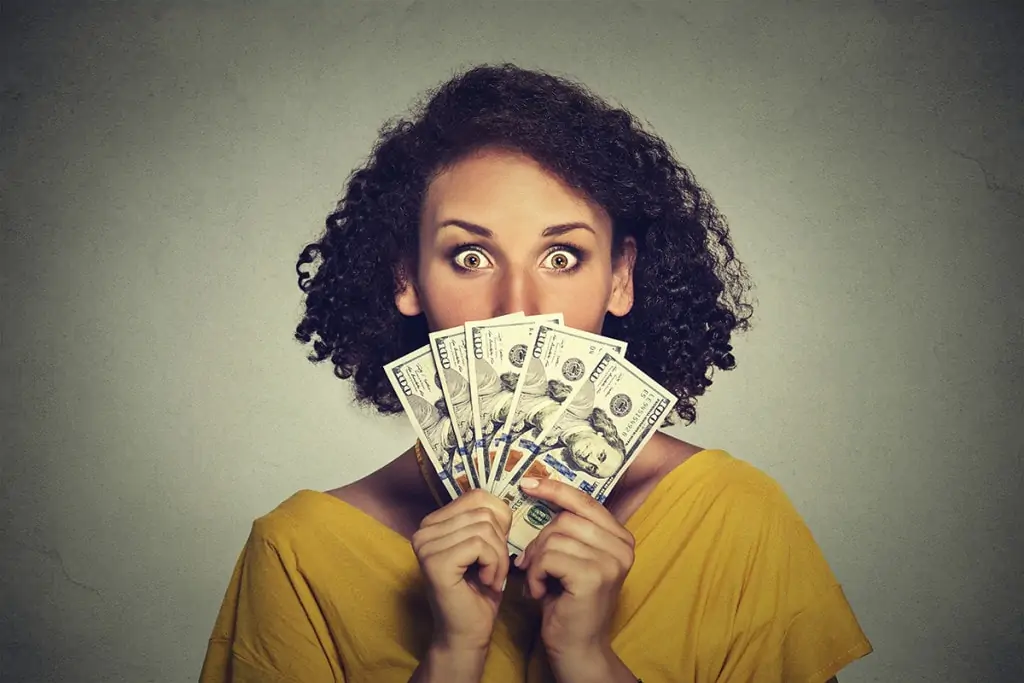 Woman evaluating LASIK price looking through a fan of dollar banknotes