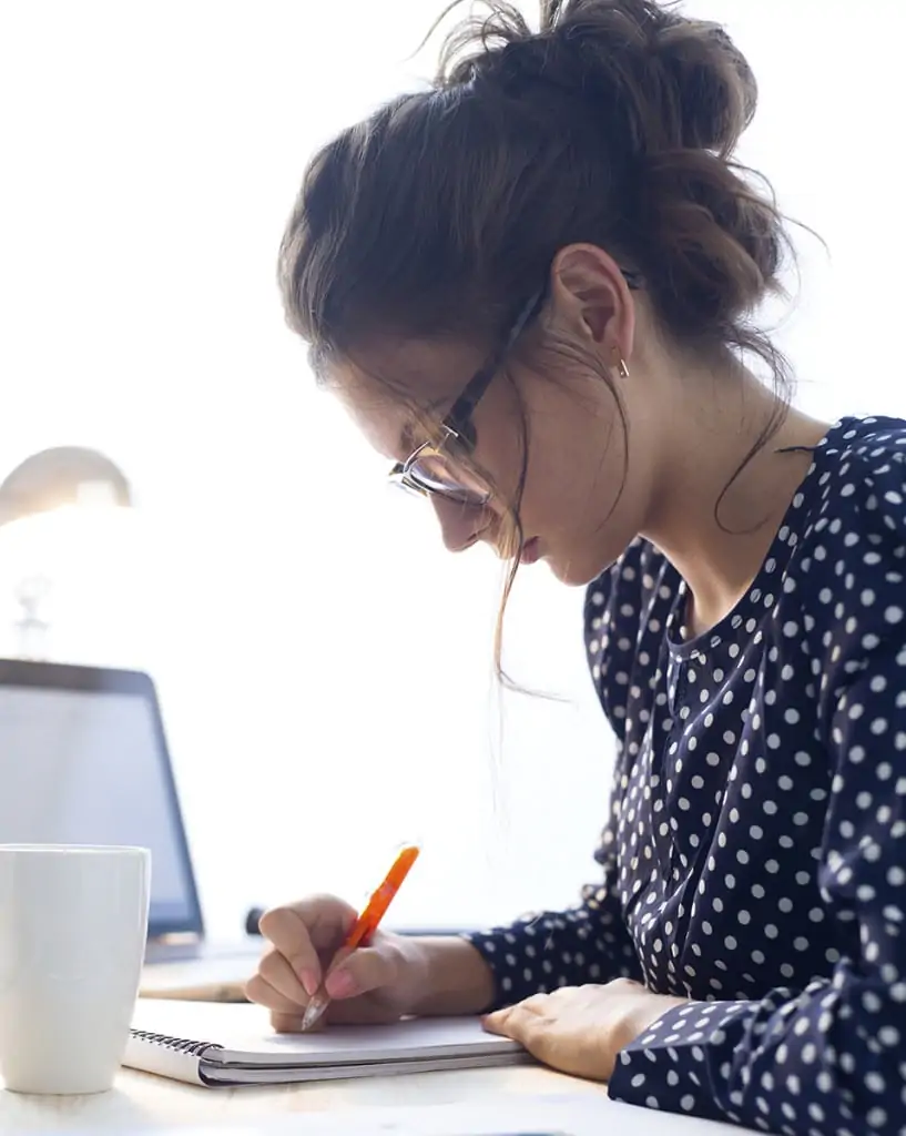 Young woman writing notes for her LASIK eye doctor on the cost of LASIK