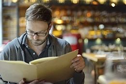 Young man choosing from the menu in a restaurant