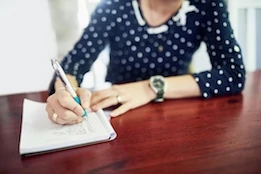 Woman writing in a notebook at a table