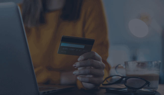 Woman in yellow shirt holding a credit card at her desk